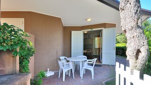 An outdoor patio with a white table and chairs, a brick floor, and a white fence. - Villaggio Tivoli by Interhome (Bibione)