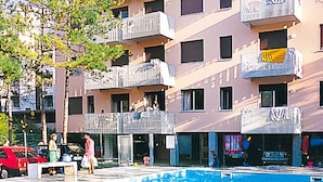 A swimming pool area with a building in the background. - Apartment Erica by Interhome (Bibione)