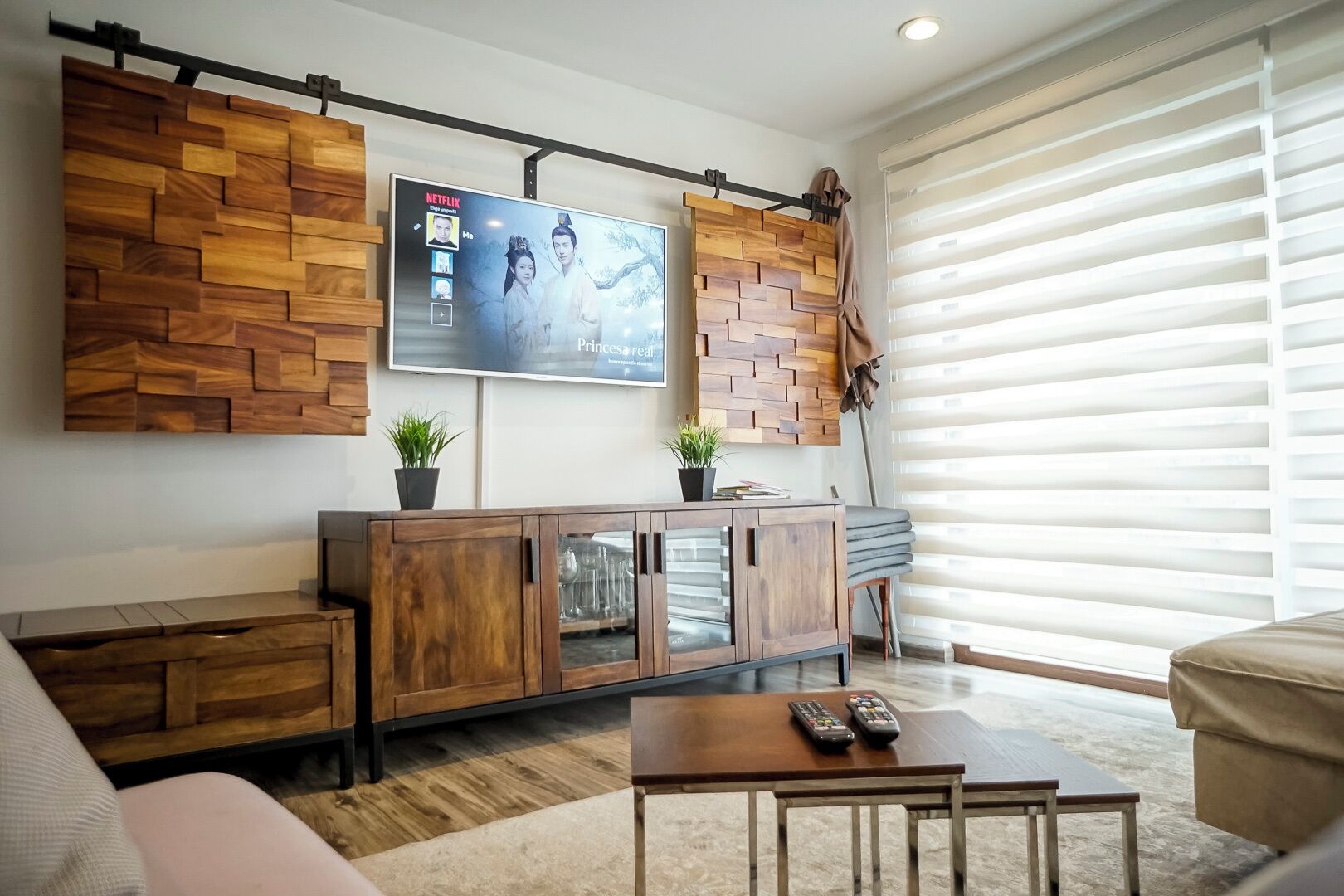 Ein modernes Wohnzimmer mit einer Wandverkleidung aus Holz, einem wandmontierten Fernseher und einem Sofa.