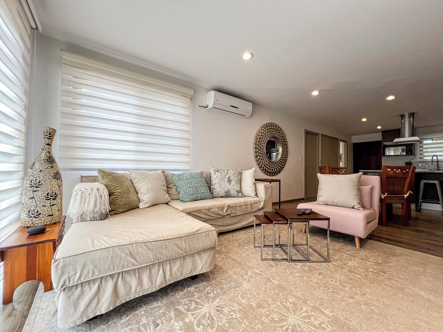Una sala de estar con un sofá, una silla, una mesa de centro y un jarrón decorativo.