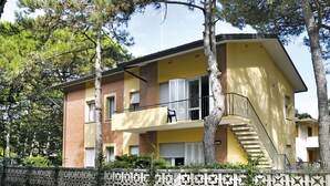 Ein zweistöckiges Gebäude mit gelber Fassade, einem Balkon und einer Treppe, die zu dem oberen Stockwerk führt.