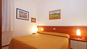 Ein Hotelzimmer mit einem Bett, Nachttischen, zwei Wandlampen und zwei gerahmten Bildern.