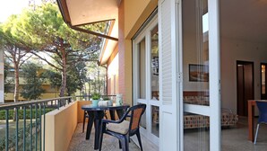 Ein Balkon mit Tisch und Stühlen, einem Blumentopf und einer Glastür zu einem Zimmer mit einem Bett.