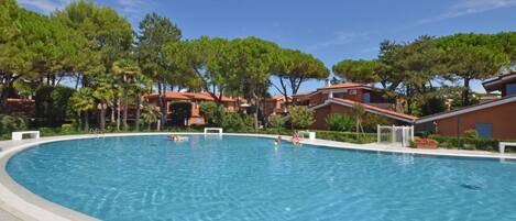 A large outdoor swimming pool surrounded by trees and buildings.