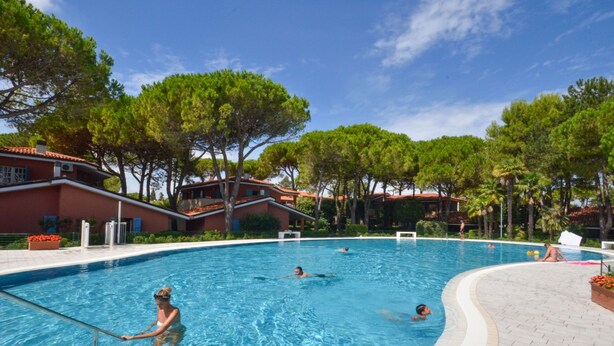 A swimming pool with clear blue water, surrounded by trees and buildings. - Villaggio Euro Residence Club by Interhome (Bibione)