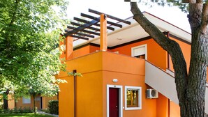 A modern building with a red door, a staircase, and a tree in front. - Villaggio Splendido by Interhome (Bibione)
