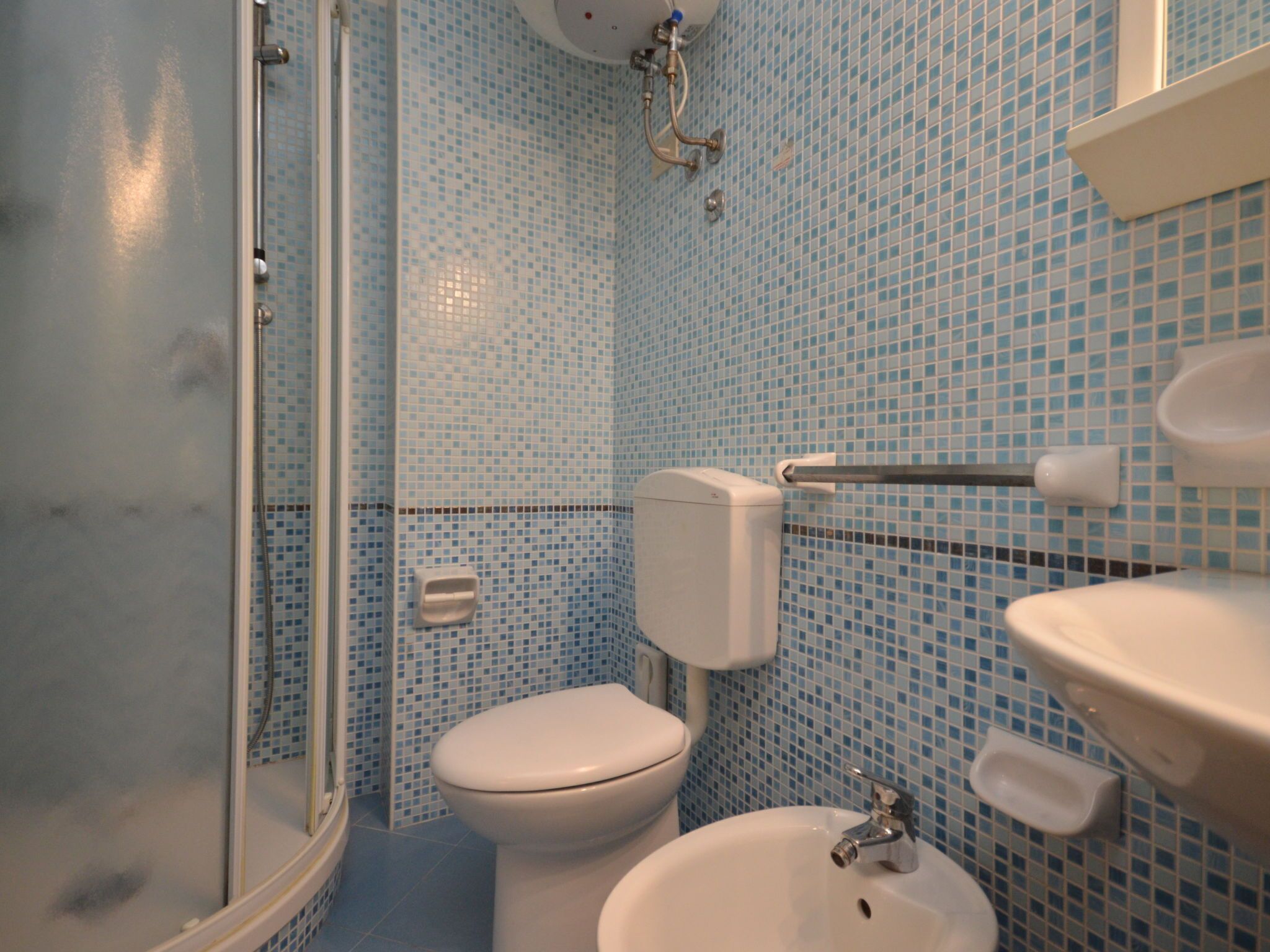 Une salle de bain avec une douche à parois de verre, des toilettes et un lavabo.