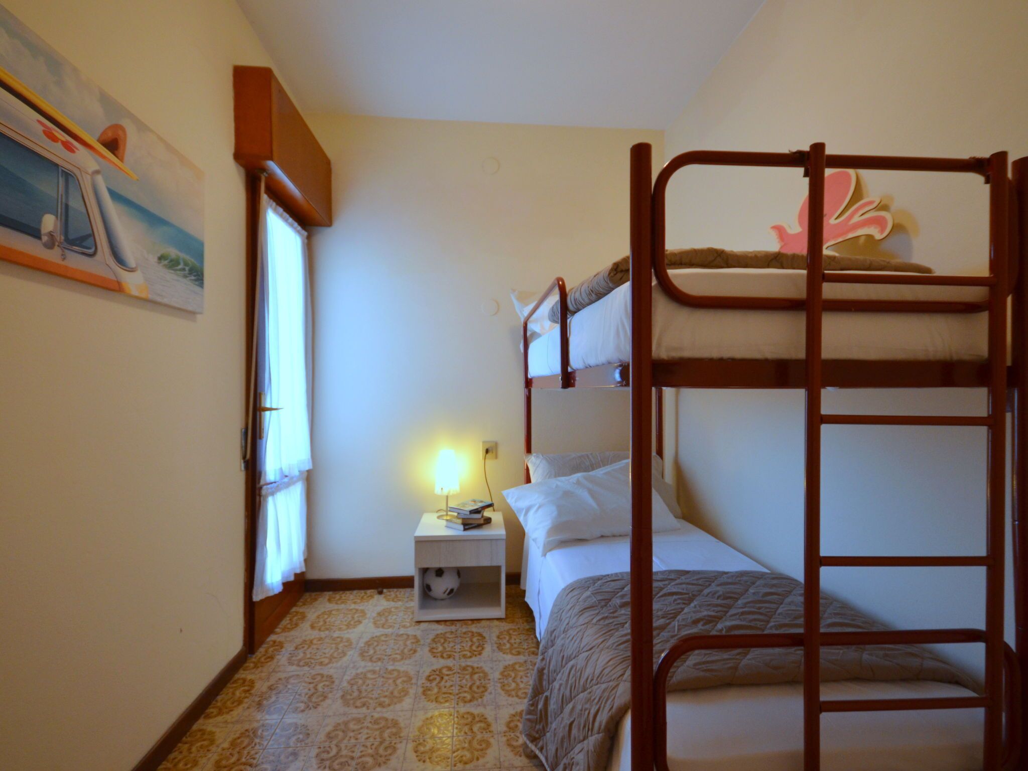 Una stanza piccola e funzionale con letti a castello, un comodino con una lampada e un pavimento decorato.