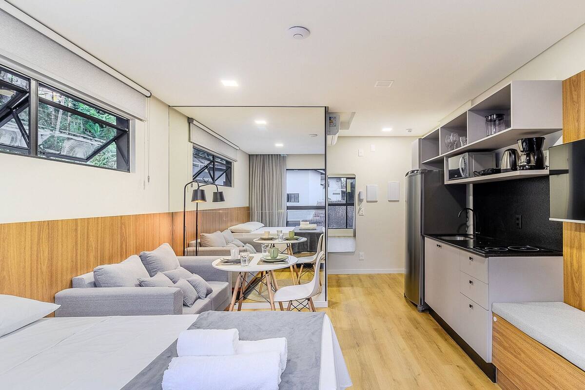 A compact hotel room with a kitchenette, a dining area, and a sofa.