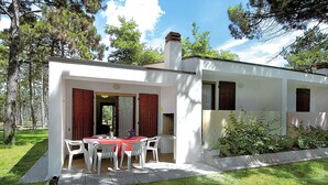A modern two-story house with a dining area featuring a red table and white chairs. - Villaggio Paradiso by Interhome (Bibione)