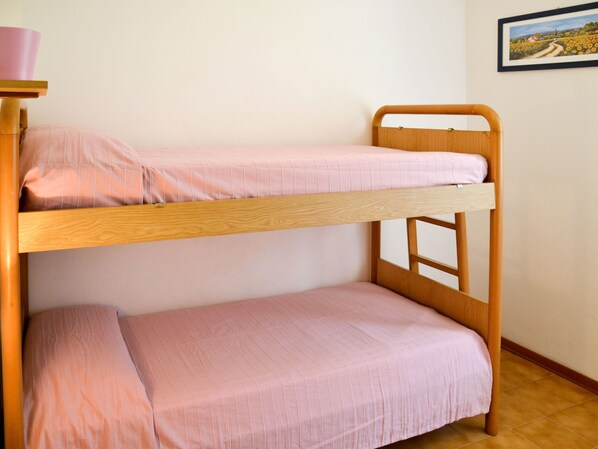 A bunk bed with pink bedding in a room with a tiled floor and a framed picture on the wall.