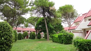 Une cour agrémentée de haies soigneusement taillées, d’une pelouse verdoyante et d’une rangée de bâtiments aux toits rouges.