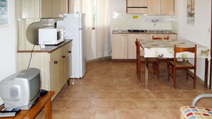 A compact kitchen with a microwave, refrigerator, and a small dining table with chairs.