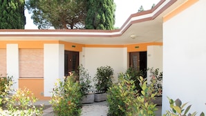A courtyard with a gravel path, potted plants, and a building with a beige and orange facade.