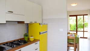 Una cocina con armarios blancos, un refrigerador amarillo, una estufa y una zona de comedor con una mesa y sillas.
