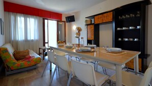 Un comedor con una mesa larga, sillas blancas y una pared de acento roja.