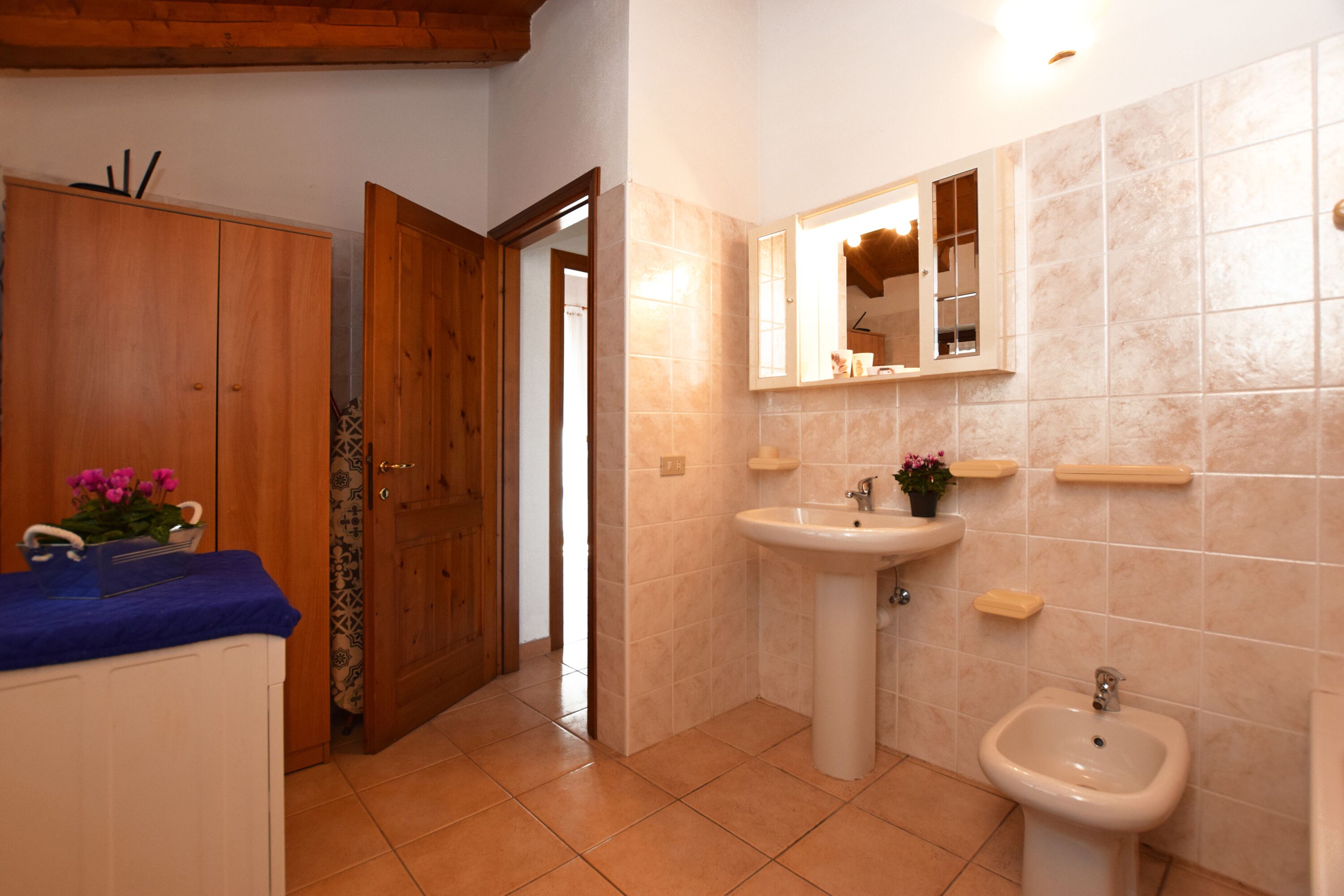 Casa de banho com guarda-roupa de madeira, lavatório, bidé e espelho.