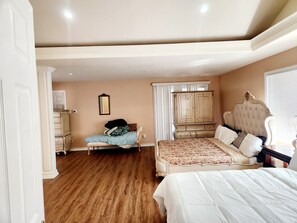 A bedroom with a large bed, a smaller bed, a wardrobe, and a mirror on the wall.
