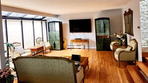 Un soggiorno spazioso con una grande televisione, parquet e vista tramite un lucernario.