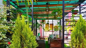 A covered garden area with artificial grass, wicker furniture, and hanging plants. - Joshean fully furnished Apartments  (Kampala)