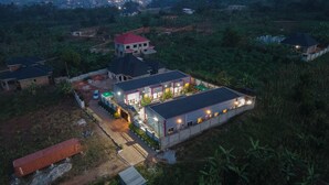 An aerial view of a residential area with multiple houses, including a large house with a red roof and a smaller house with a green roof. - Joshean fully furnished Apartments  (Kampala)