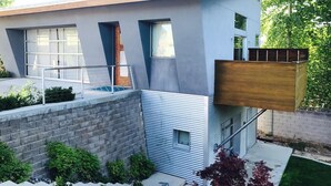 Een modern huis met twee verdiepingen, een plat dak, grote ramen en een klein balkon.