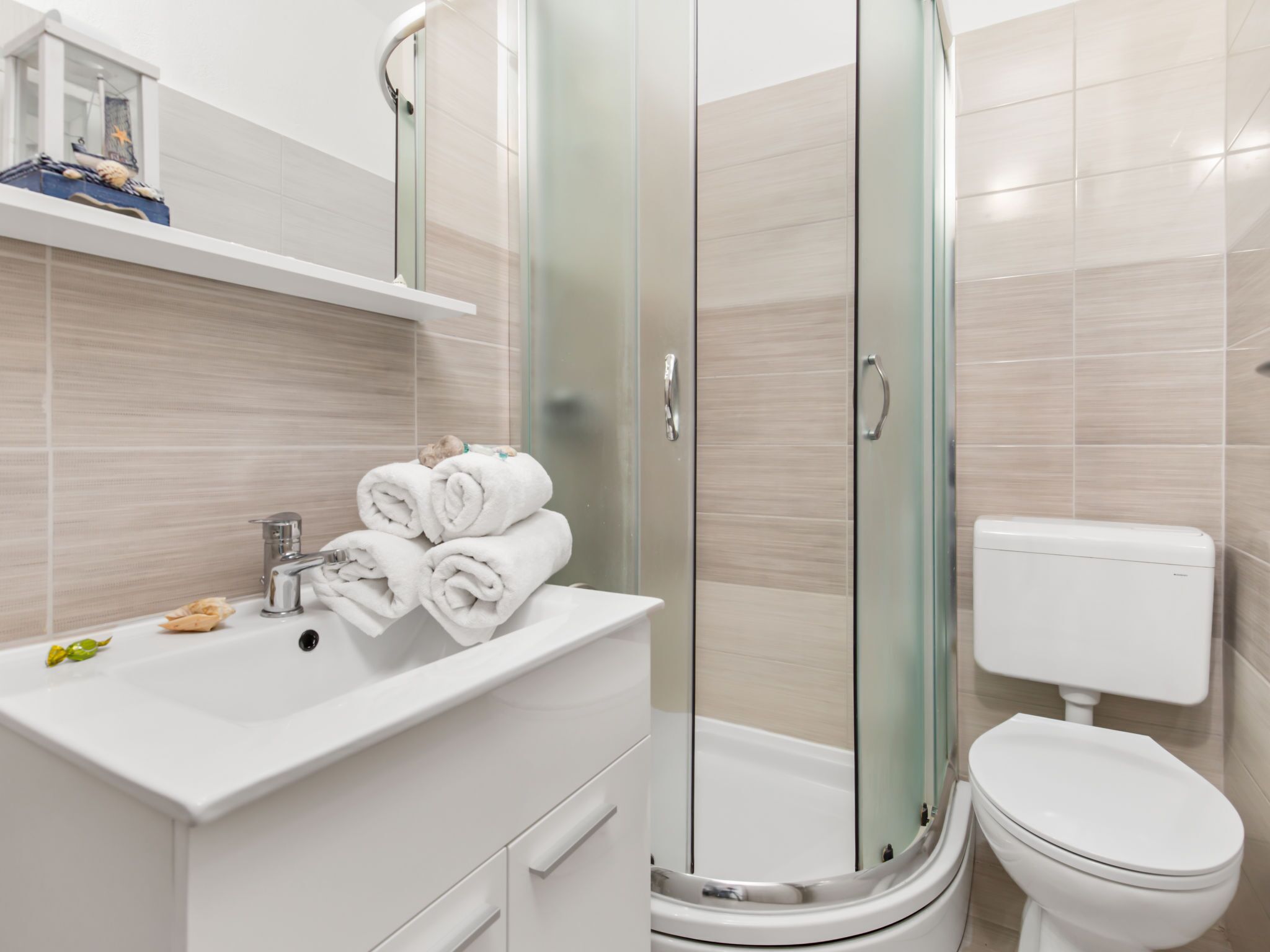 A modern bathroom with a glass-enclosed shower, a white sink, and a toilet.