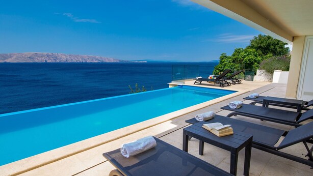 Ein Poolbereich mit Liegestühlen und Meerblick.