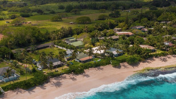 Vista aérea de una zona residencial costera con casas, una playa y el océano.