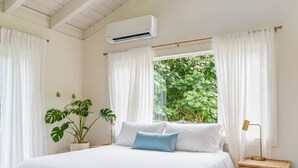 Un dormitorio con una cama, una mesita de noche, una lámpara y una planta en maceta.