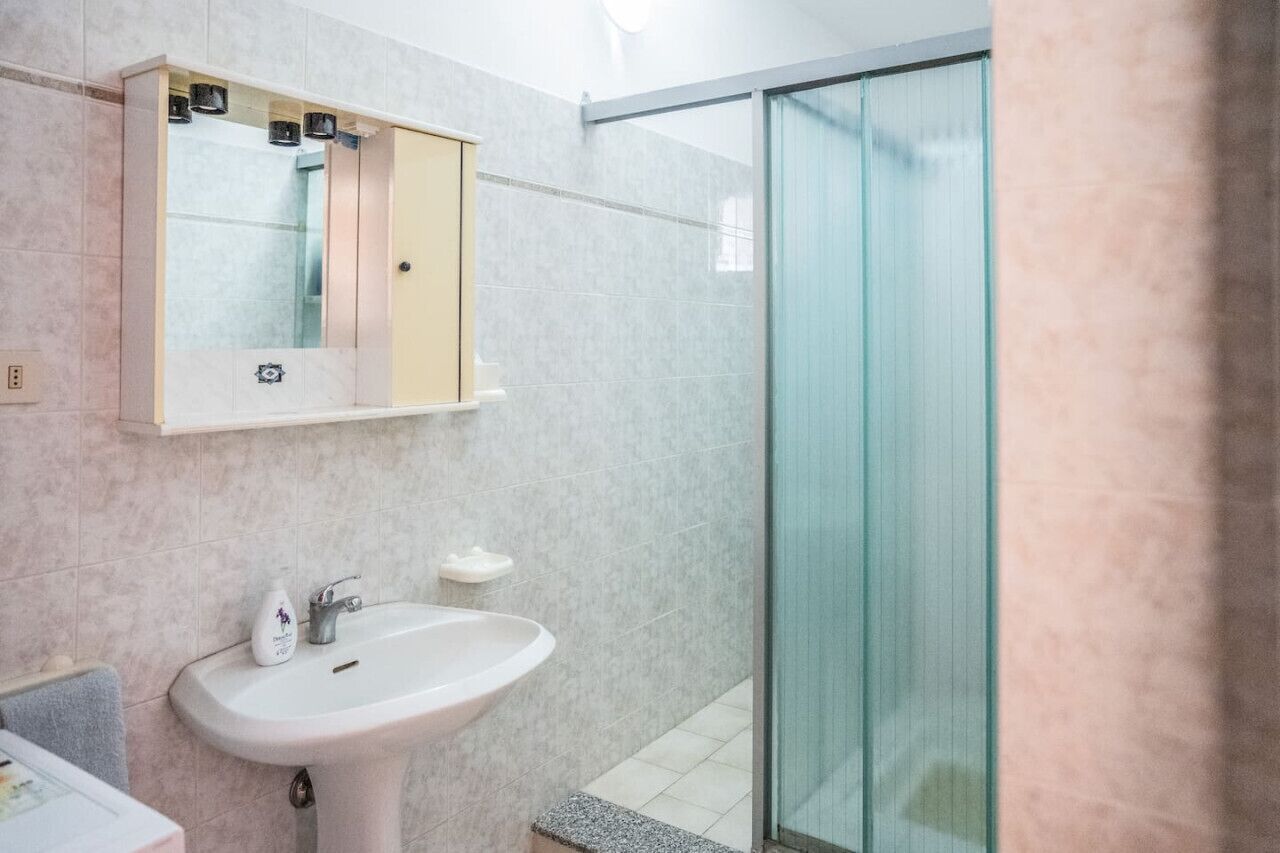 Ein Badezimmer mit Waschbecken, Spiegel und Duschkabine aus Glas.