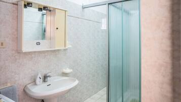Ein Badezimmer mit Waschbecken, Spiegel und Duschkabine aus Glas.