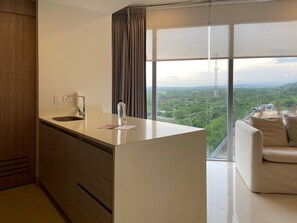 A modern kitchen with a large window, a sofa, and a view of a green landscape.