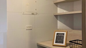 A laundry area with a Samsung washing machine, a framed picture of icons, and a black basket on a wooden shelf. - w Majestic 1BR w AC in Sunny Cartagena (Cartagena)