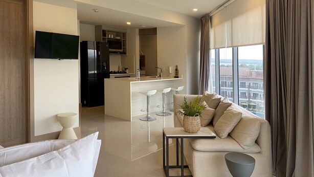 A modern living room with a sofa, a coffee table, and a TV. There is a kitchen area with a dining table and chairs. - w Majestic 1BR w AC in Sunny Cartagena (Cartagena)