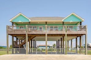 A two-story building with a balcony, wooden structure, and a fenced area. - King Bed, Pet Friendly. Sleeps 8 (Bolivar Peninsula)