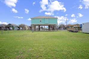 A residential area with a prominent turquoise house in the center, surrounded by other similar houses. - King Bed, Pet Friendly. Sleeps 8 (Bolivar Peninsula)