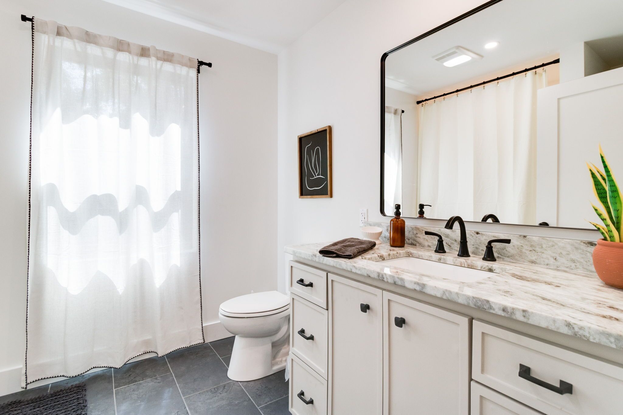 Une salle de bain avec des toilettes, un lavabo avec un miroir et un rideau de douche.
