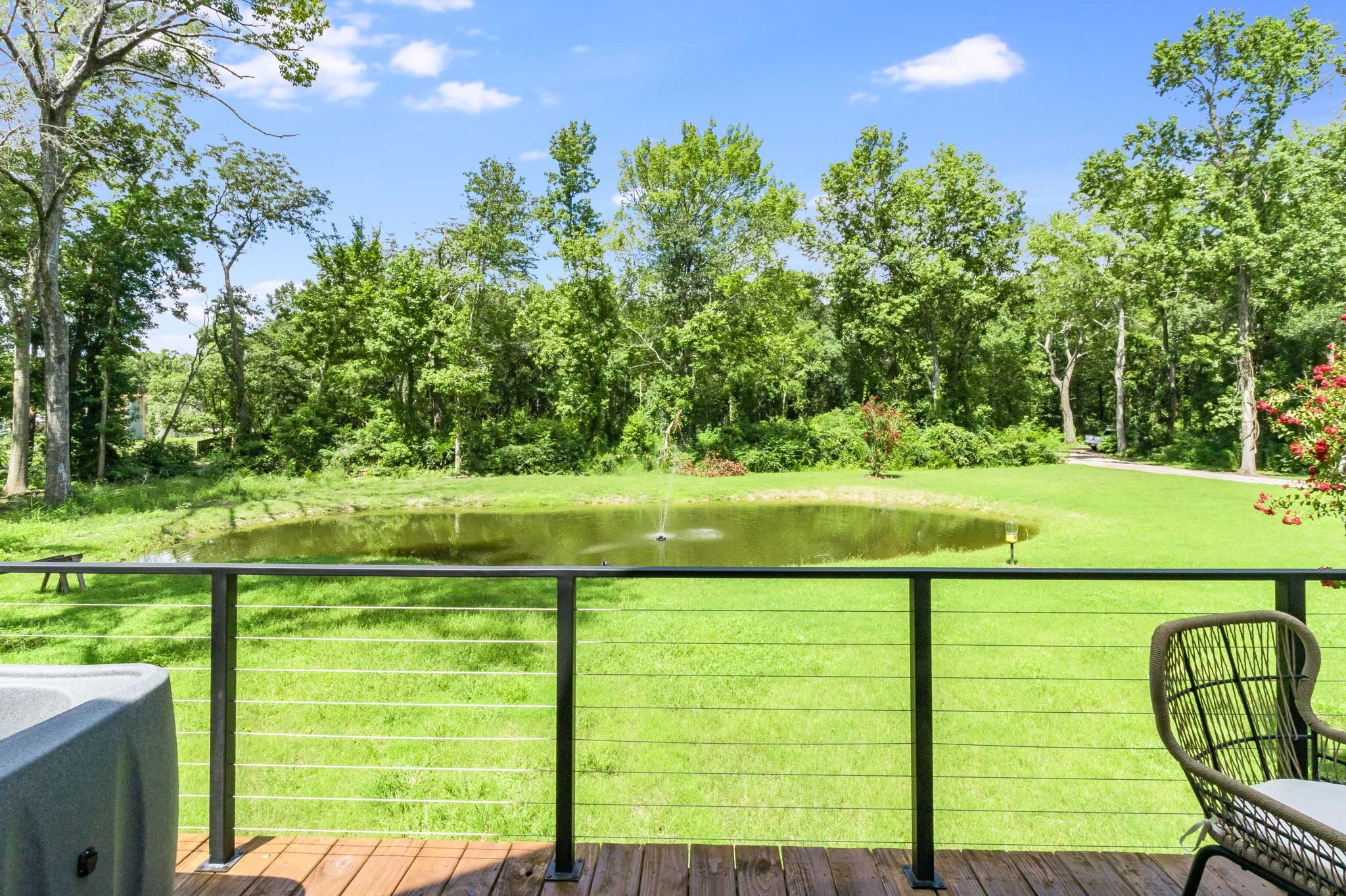Une terrasse avec vue sur un étang, des arbres et une zone herbeuse.