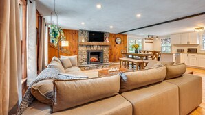 Ein gemütliches Wohnzimmer mit Kamin, einer Couch und einem Essbereich mit Tisch und Stühlen.