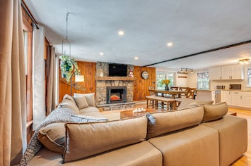 Cozy up in our charming living room, featuring a rustic stone fireplace and open layout that seamlessly connects to the dining and kitchen areas. Perfect for gatherings and creating lasting memories.