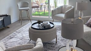 A modern living room with a large sliding glass door to a balcony, white furniture, and a patterned rug. - Spacious Apartment in Prime West Hollywood - Steps from Restaurants & Night life (Los Angeles)