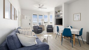 Un salon moderne comprenant un canapé, des fauteuils, une table à manger et un ventilateur de plafond.