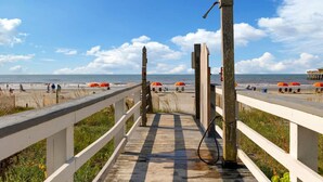 A wooden boardwalk leading to a beach with umbrellas and people. - Front Beach Condo! 1 Block to Center Street-3C (Folly Beach)