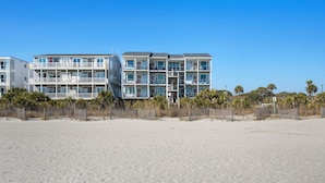 A beachfront hotel with multiple balconies, a sandy beach in front, and a clear blue sky. - Front Beach Condo! 1 Block to Center Street-3C (Folly Beach)