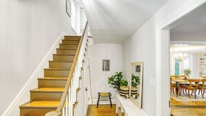 A staircase with wooden steps and white railings leading to a room with a wooden floor, a bench, and a large mirror. - Historic Catskills Farmhouse: Ski, Hike & Relax! (Catskill)