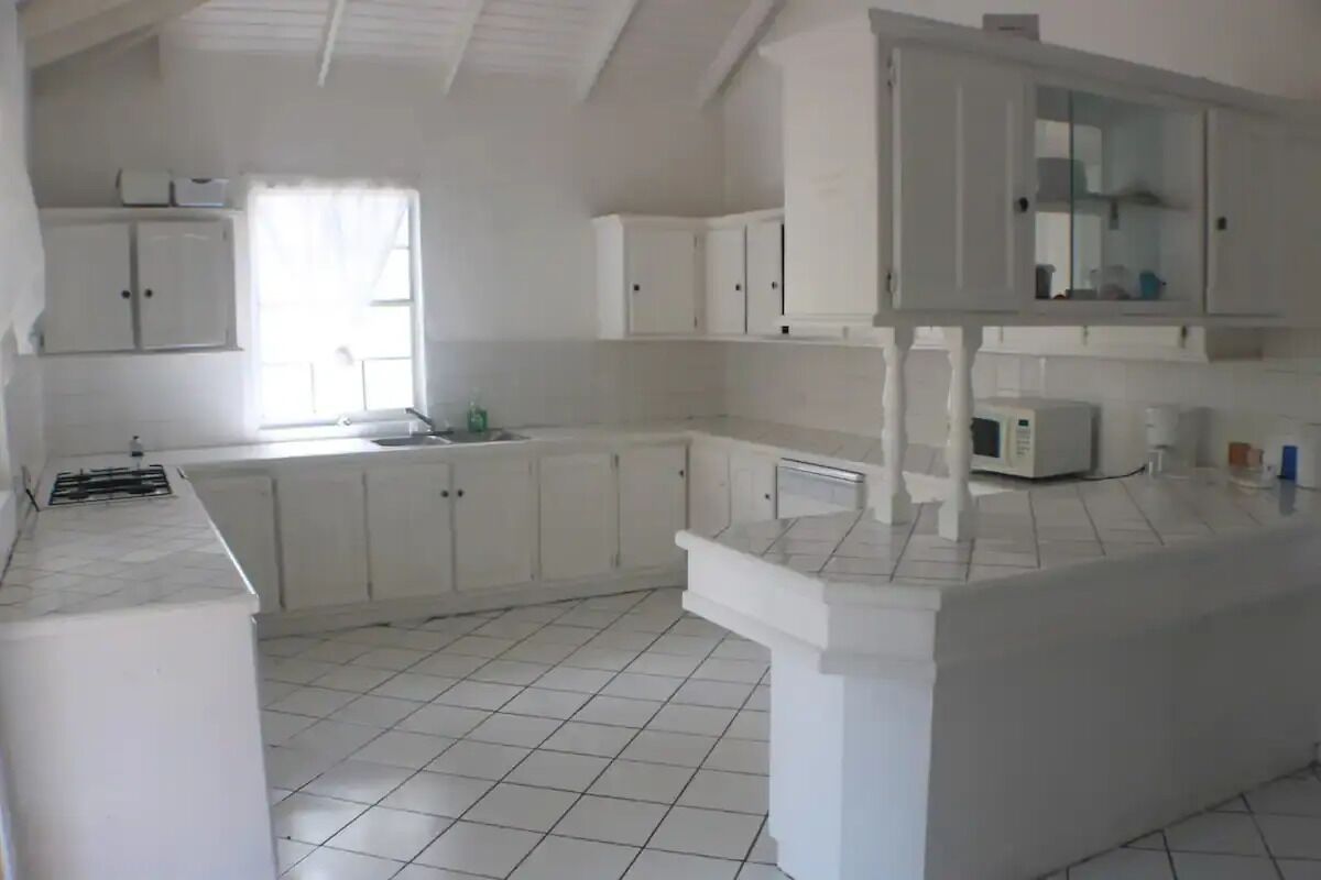 A kitchen with white cabinets, a microwave, and a tiled floor.