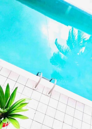 En swimmingpool med en kakelbeklädd poolkant och en metallstege.