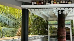 Un espace bar avec une variété de bouteilles d’alcool et de verres suspendus au plafond.