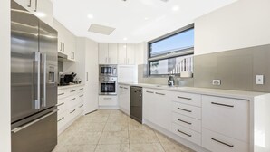 A modern kitchen with stainless steel appliances, white cabinetry, and a large window providing natural light.
